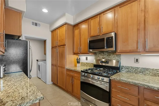 a kitchen with stainless steel appliances granite countertop a stove a refrigerator and a microwave