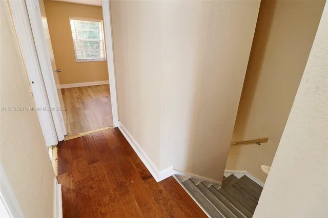 an empty room with wooden floor and fan