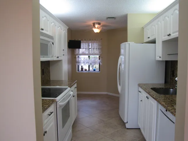a kitchen with stainless steel appliances granite countertop a refrigerator a stove and a sink