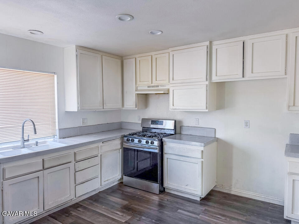 1253 Morven Street Lancaster, CA 93535 - Photo 4 of 18 a kitchen with cabinets appliances a sink and wooden floor