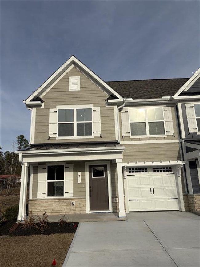 View of front of house featuring driveway, a garage, and stone siding