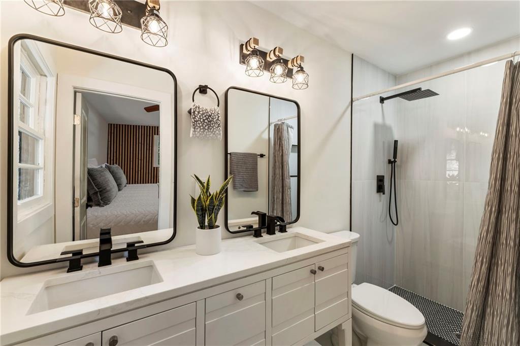 1690 Carter Road Decatur, GA 30032 - Photo 32 of 49 a bathroom with a double vanity sink toilet mirror and shower
