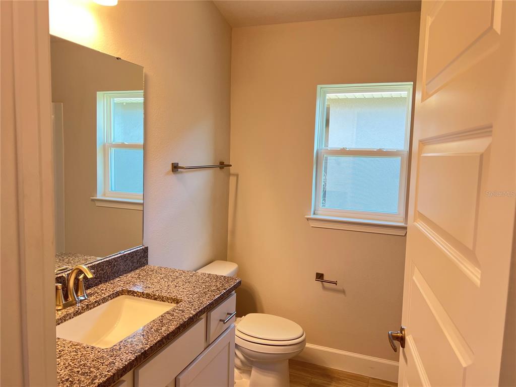 13322 Ogden Glade Road Dade City, FL 33525 - Photo 15 of 24 a bathroom with a granite countertop sink a mirror and a toilet