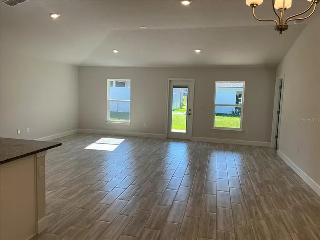 a view of kitchen with granite countertop refrigerator and white cabinets