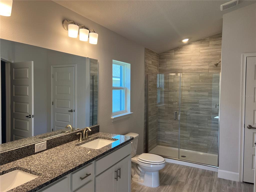 13322 Ogden Glade Road Dade City, FL 33525 - Photo 9 of 24 a bathroom with a granite countertop sink toilet and shower