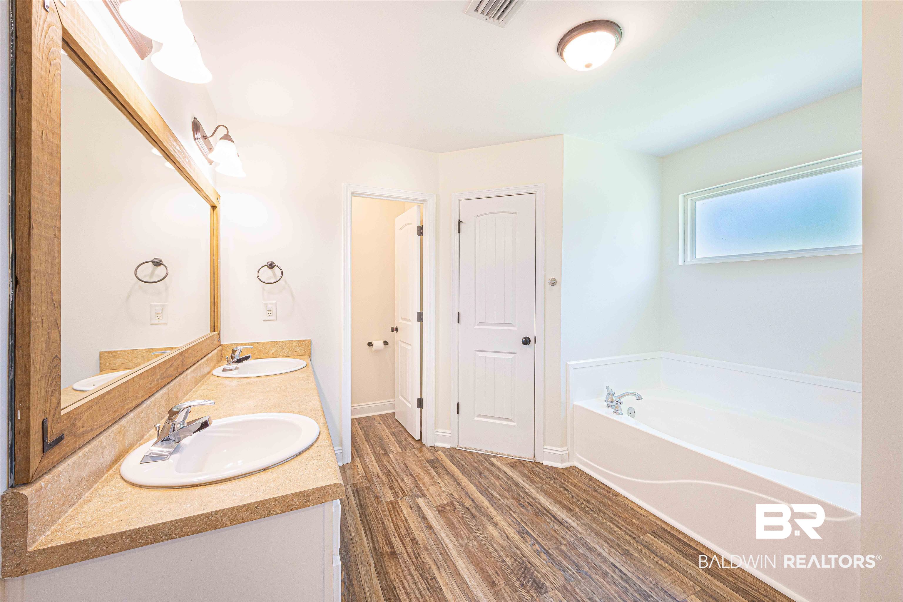 18675 Explorer Drive Loxley, AL 36551 - Photo 22 of 42 Full bathroom featuring a garden tub, wood finished floors, and double vanity