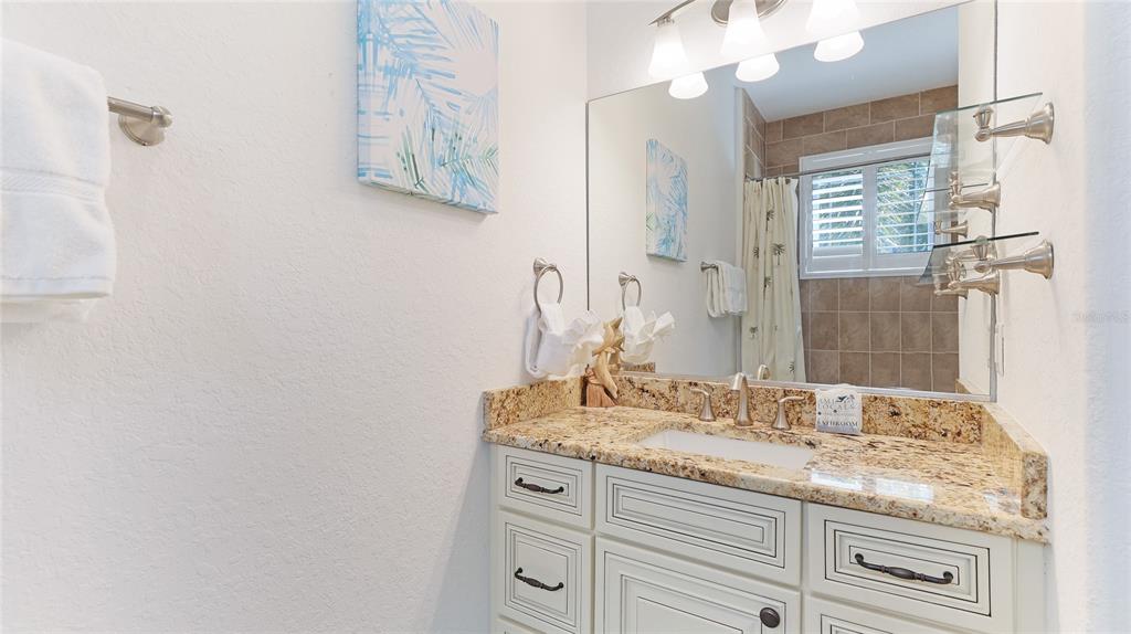 4101 4th Avenue Holmes Beach, FL 34217 - Photo 27 of 60 a bathroom with a granite countertop sink a mirror and a shower