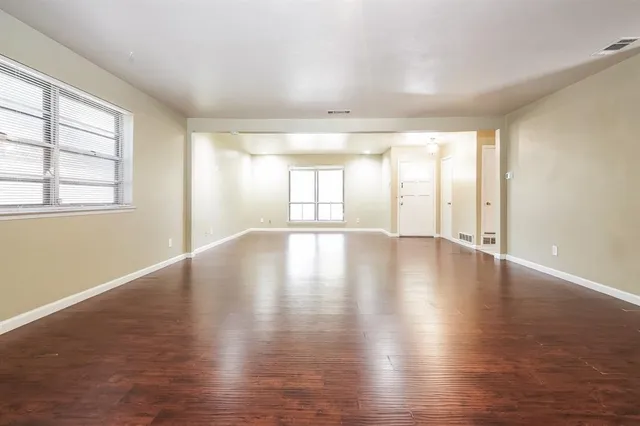 a view of an empty room with wooden floor and a window