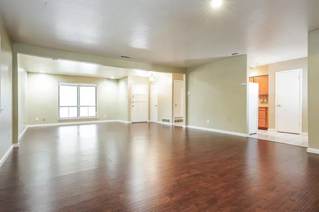 a view of an empty room with window and wooden floor