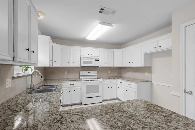 a kitchen with cabinets appliances a sink and a window