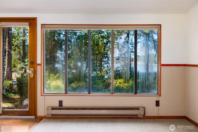 a view of an empty room with window and kitchen view