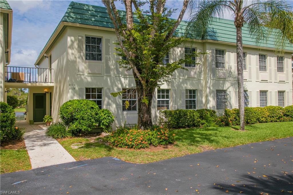 217 Bobolink Way, Unit 217B Naples, FL 34105 - Photo 12 of 17 a front view of a residential apartment building with a yard and potted plants