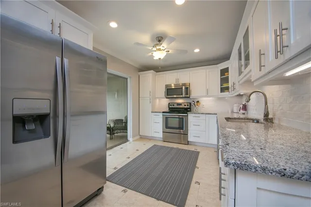 a kitchen with kitchen island granite countertop a refrigerator a sink a stove and cabinets