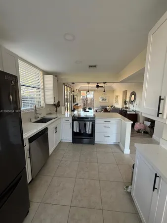 a kitchen with a sink a counter top space appliances and cabinets