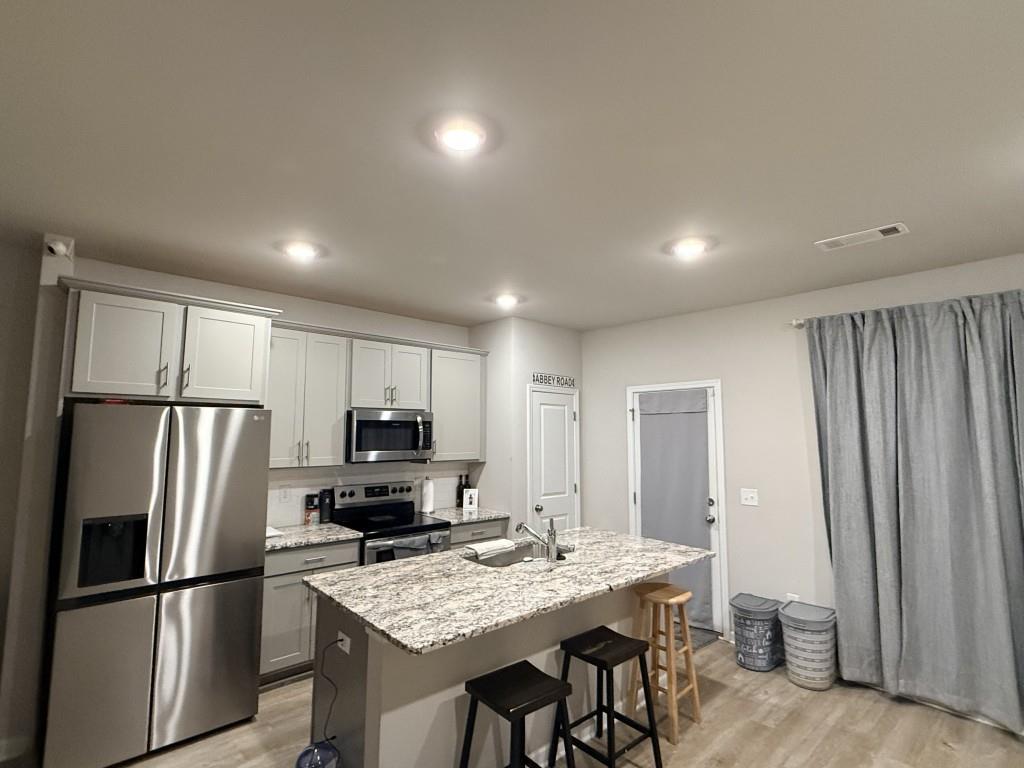 6271 Redan Square, Unit 83 Lithonia, GA 30058 - Photo 9 of 10 a kitchen with kitchen island a refrigerator stove microwave and cabinets