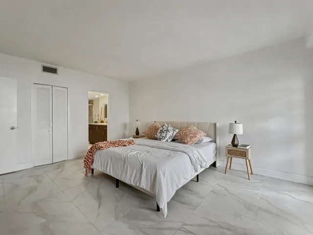 a spacious bedroom with a bed and a lamp