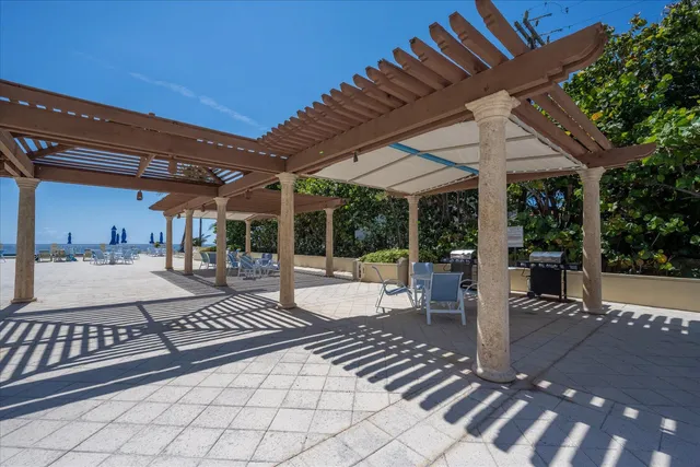 a view of a patio with a dining table and chairs with a barbeque grill and a table