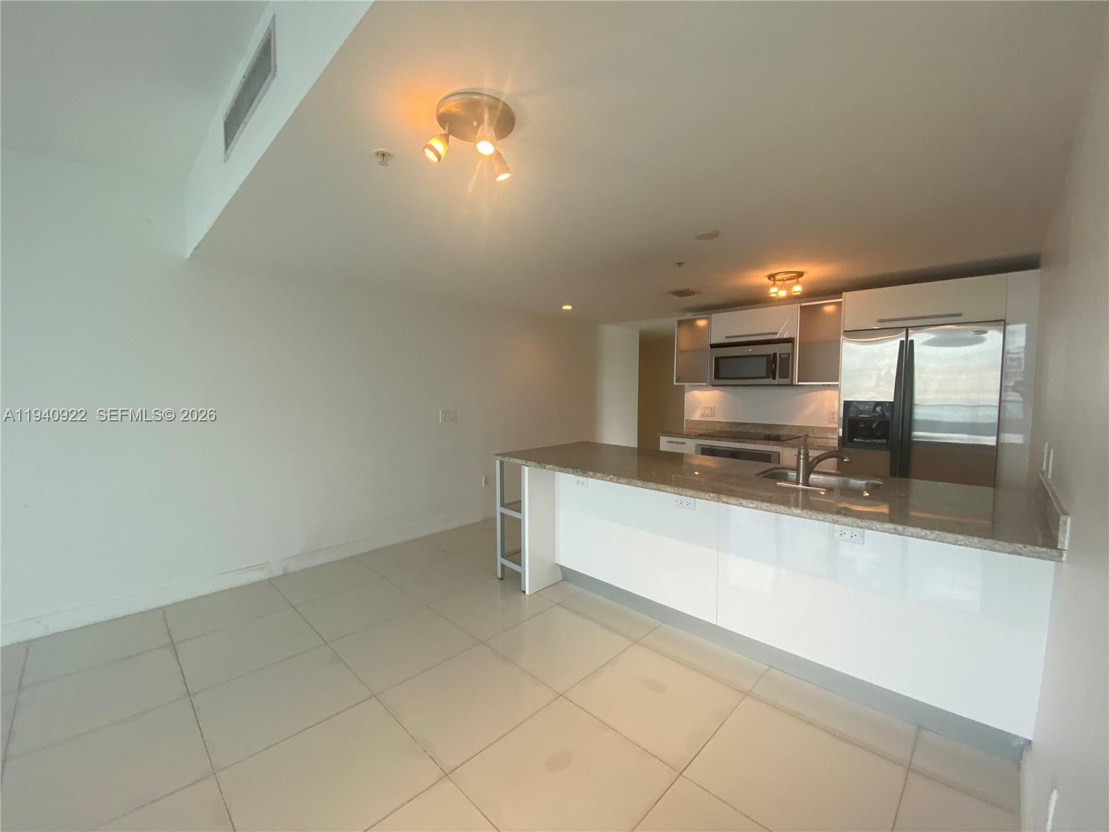 185 Southwest 7th Street, Unit 501 Miami, FL 33130 - Photo 3 of 31 a large kitchen with kitchen island granite countertop a sink and white cabinets