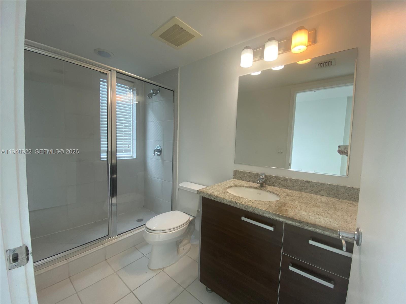 185 Southwest 7th Street, Unit 501 Miami, FL 33130 - Photo 10 of 31 a bathroom with a granite countertop sink toilet and shower