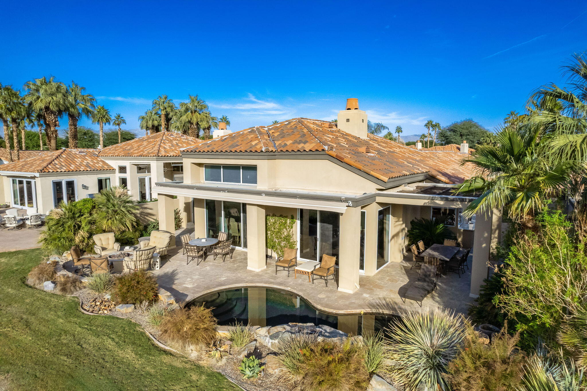 56685 Merion La Quinta, CA 92253 - Photo 74 of 82 a view of a white house with a swimming pool and lawn chairs with potted plants