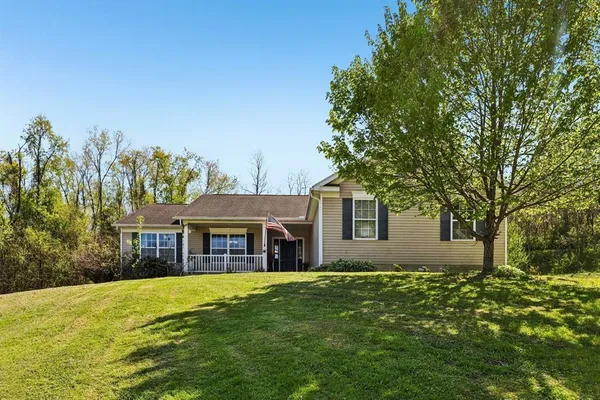 a front view of house with yard and trees in the background