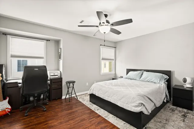 a bedroom with a bed a dresser and wooden floor