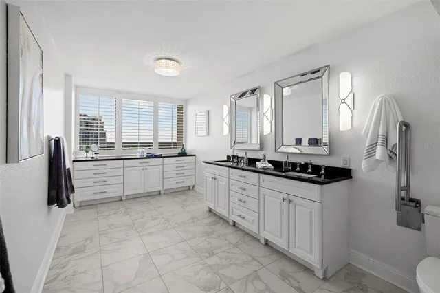 a large white kitchen with a sink a window and stainless steel appliances