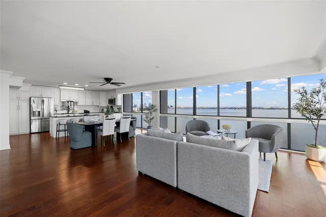 a living room with couches and a large window with kitchen view