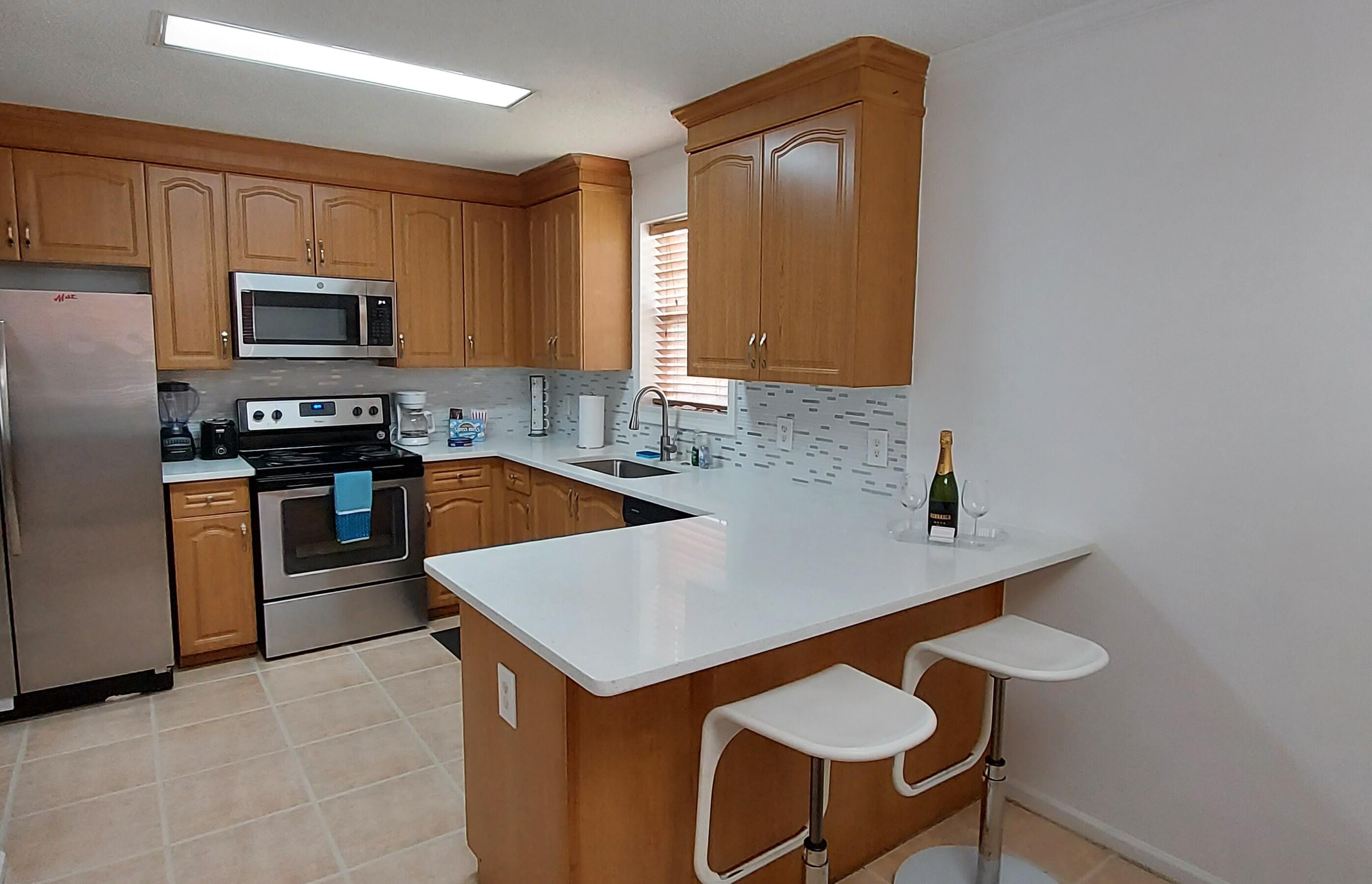 1401 West 9th Street Riviera Beach, FL 33404 - Photo 2 of 17 a kitchen with stainless steel appliances granite countertop a sink a stove top oven a counter space and cabinets