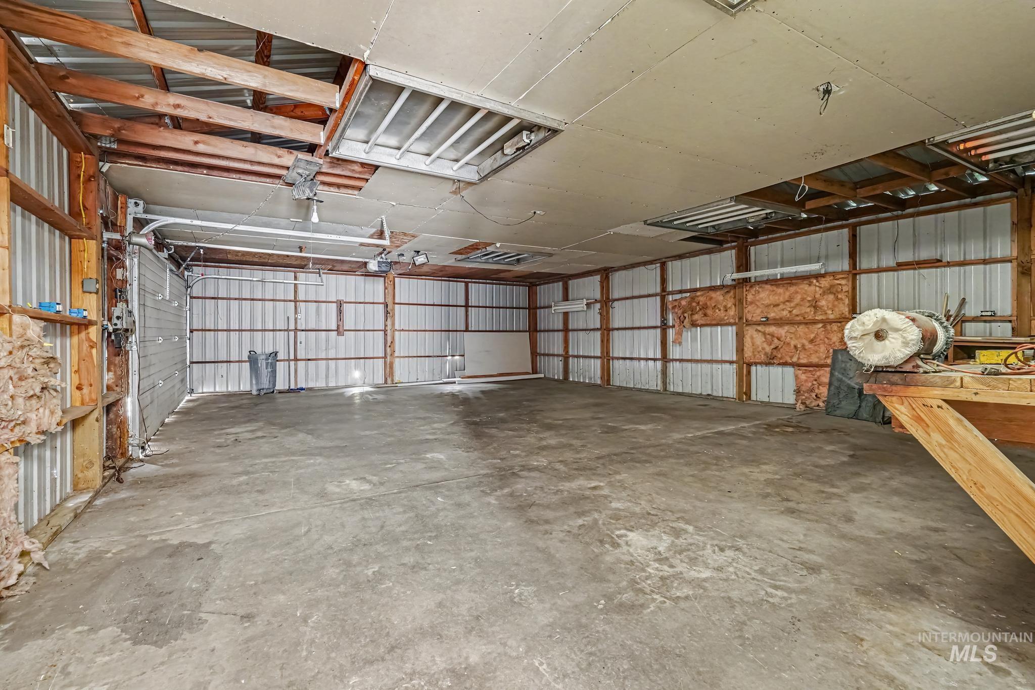 1023 State Street Weiser, ID 83672 - Photo 24 of 25 Spacious workshop featuring a concrete floor, corrugated metal walls, exposed wood framing, and multiple overhead light fixtures