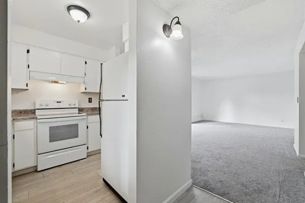 a kitchen with granite countertop white cabinets and white appliances