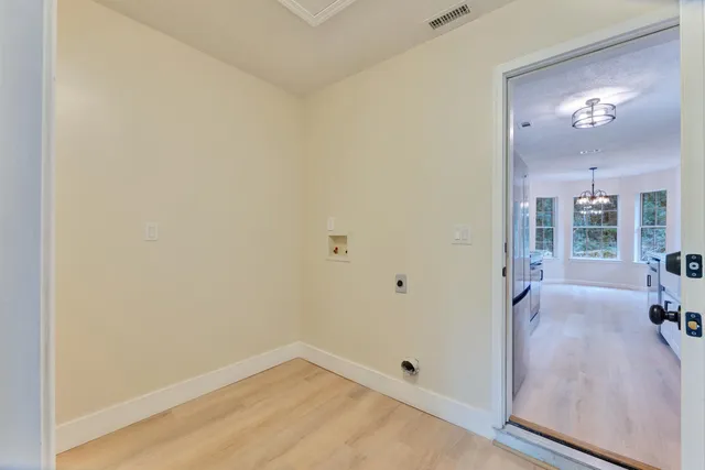 an empty room with chandelier fan and windows