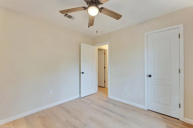 a view of an empty room and chandelier fan