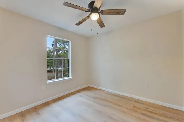 an empty room with a window and a fan