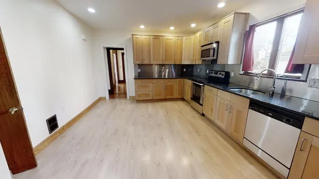 a large kitchen with a window and stainless steel appliances