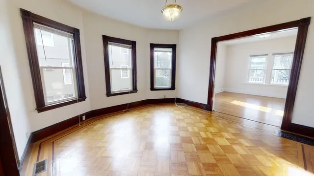 a view of an empty room with window and wooden floor