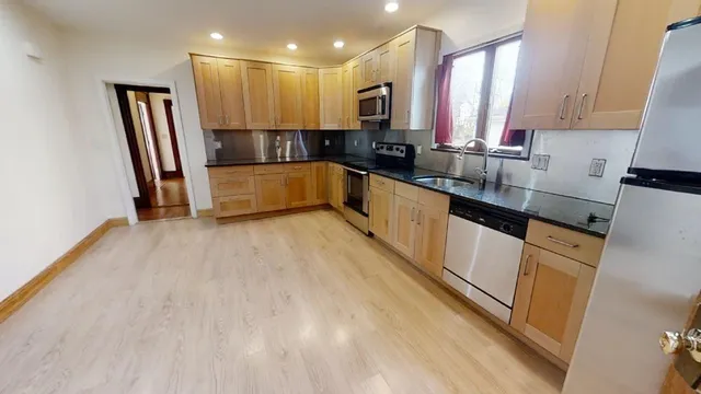 a large kitchen with stainless steel appliances a large counter top a stove a sink and a refrigerator