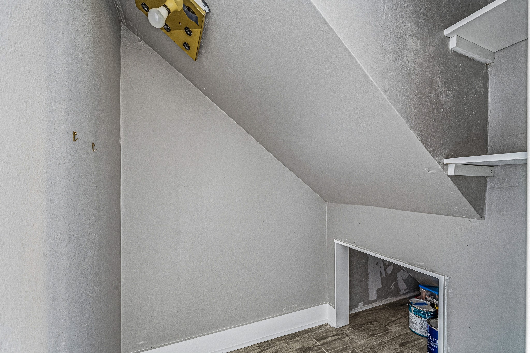 830 Threadneedle Street, Unit 240 Houston, TX 77079 - Photo 17 of 33 This photo shows a small, triangular-shaped storage space under a staircase. The area has light gray walls, a sloped ceiling, and some shelves. It's ideal for additional storage or a compact utility area.