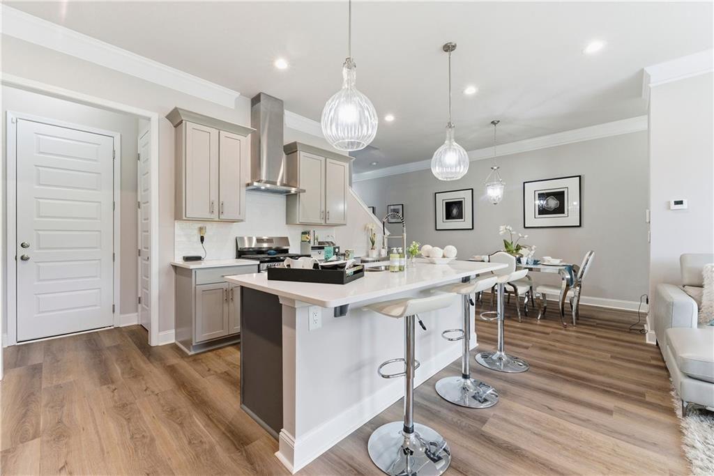 a large kitchen with granite countertop a stove a sink a dining table and chairs with wooden floor