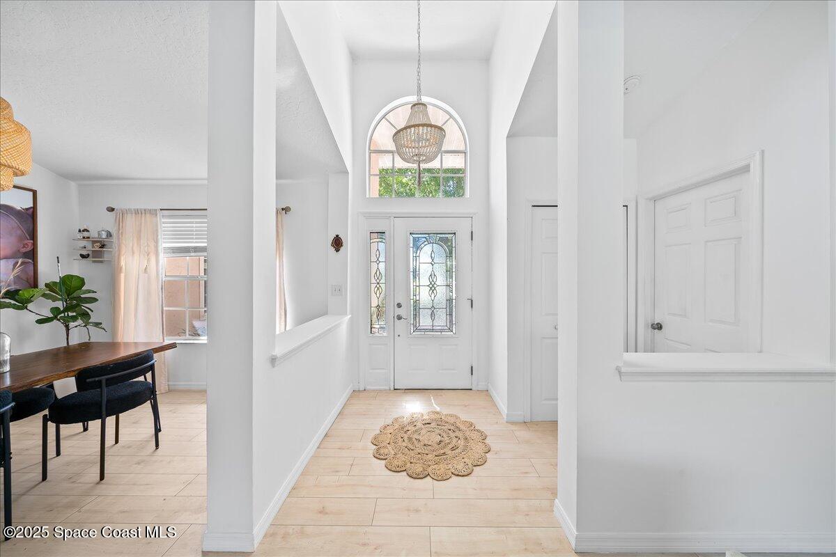 3510 Holly Springs Road Melbourne, FL 32934 - Photo 3 of 25 a hallway with a dining table and a chandelier
