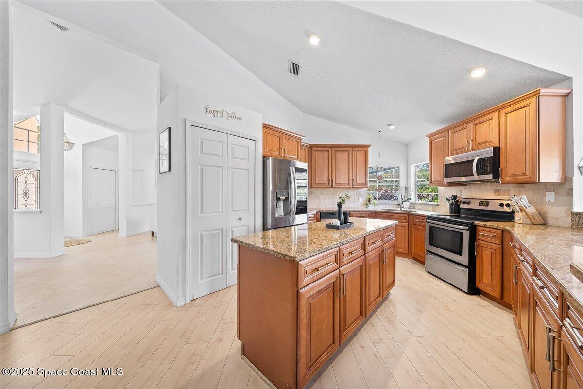 3510 Holly Springs Road Melbourne, FL 32934 - Photo 7 of 25 a kitchen with stainless steel appliances granite countertop a stove top oven a sink dishwasher a refrigerator and a refrigerator