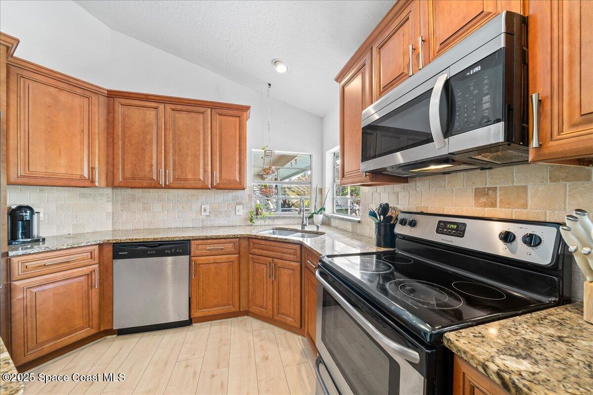 3510 Holly Springs Road Melbourne, FL 32934 - Photo 8 of 25 a kitchen with stainless steel appliances granite countertop a stove microwave sink and cabinets