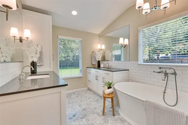 a bathroom with a granite countertop sink and a bathtub