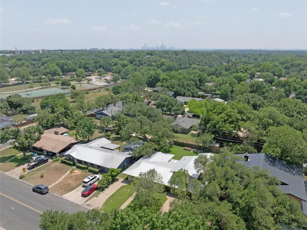 an aerial view of residential houses with outdoor space and trees