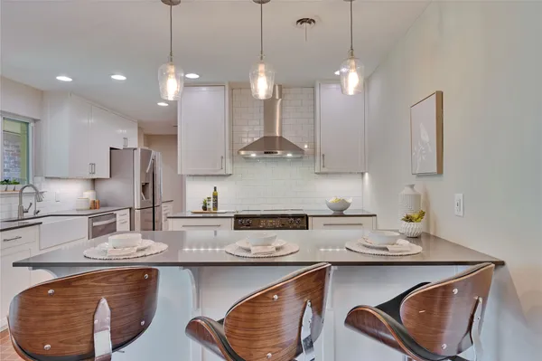 a kitchen with stainless steel appliances granite countertop a sink a stove a refrigerator and cabinets