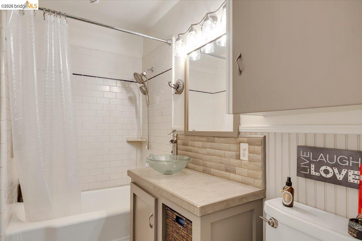 26144 Long Barn Road Long Barn, CA 95335 - Photo 20 of 42 Bathtub with subway tile surround, vanity with vessel sink, tiled countertop, beadboard wainscoting, and upper cabinetry