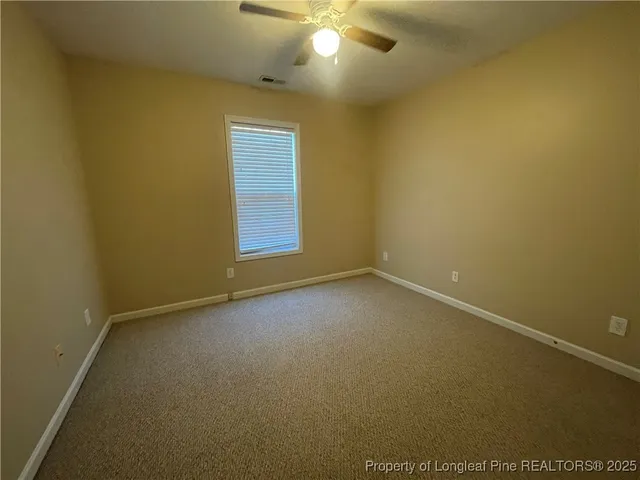 an empty room with a window and a ceiling fan