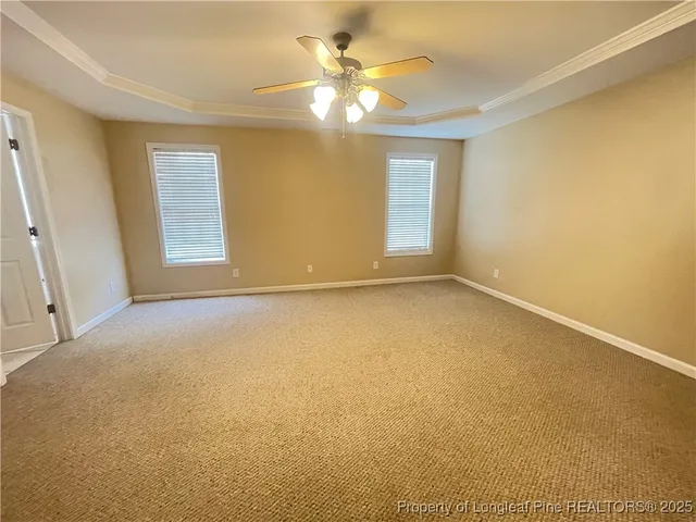 an empty room with a chandelier fan and windows