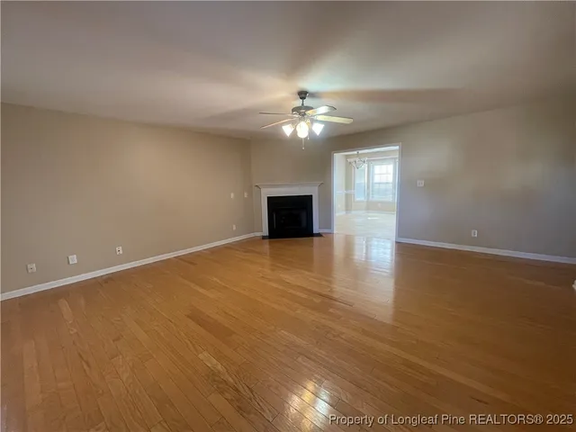 an empty room with chandelier fan and windows