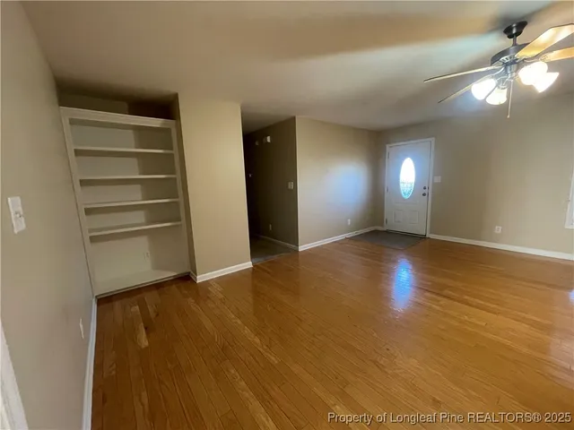 a view of an empty room with window and wooden floor